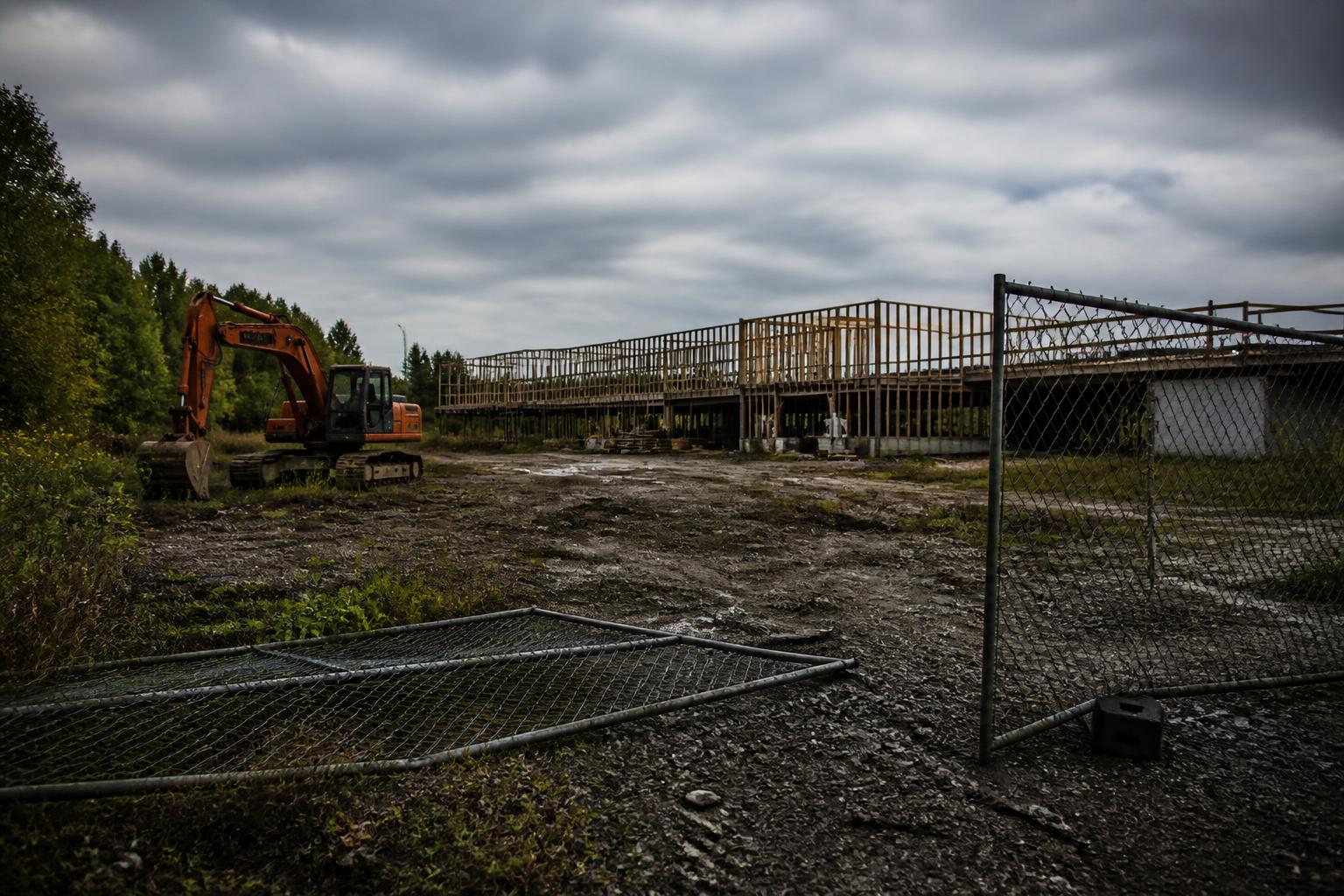 An abandoned job site with unfinished framing and idle equipment